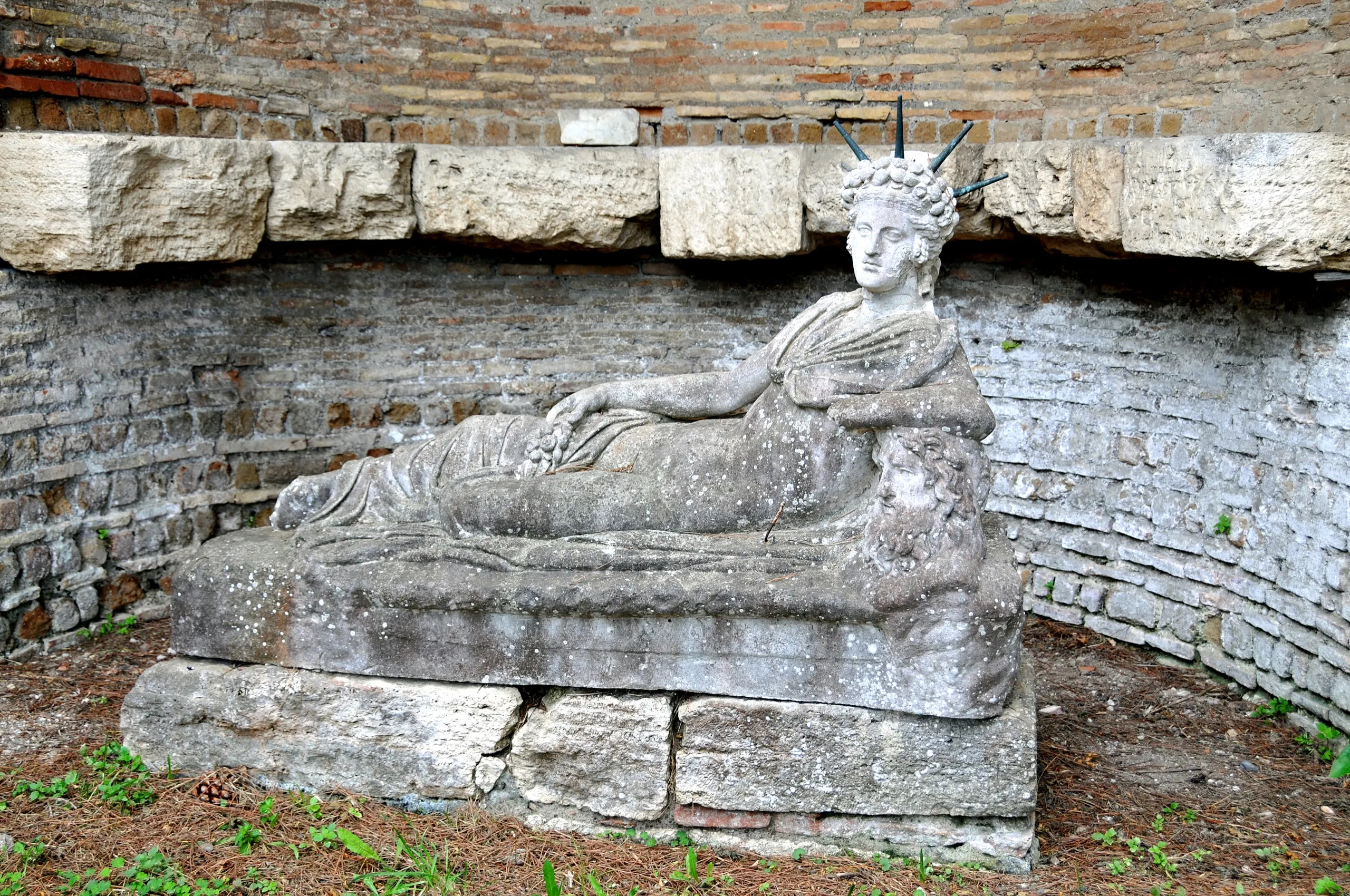 «Atis reclinado», de autoría anónima romana (época adrianea). Vaciado de yeso expuesto en el santuario de Atis de Ostia Antica, en el mismo lugar donde apareció la pieza; el mármol original se conserva en los Museos Vaticanos, Museo Gregoriano Profano (inv. 10785). Fotografía de Dennis G. Jarvis (2010), licencia CC BY-SA 2.0.