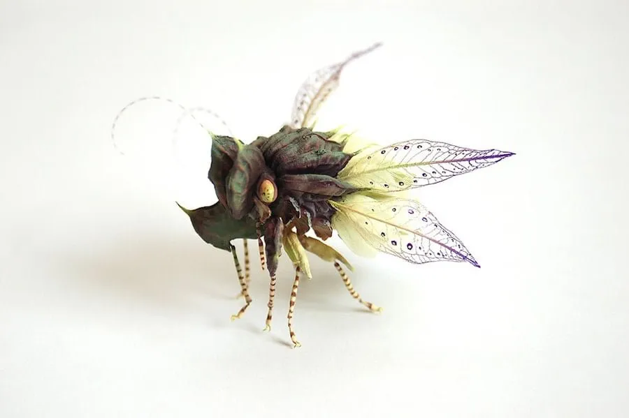 Escultura de Hiroshi Shinno de un insecto imaginario con alas de hoja verde y púrpura