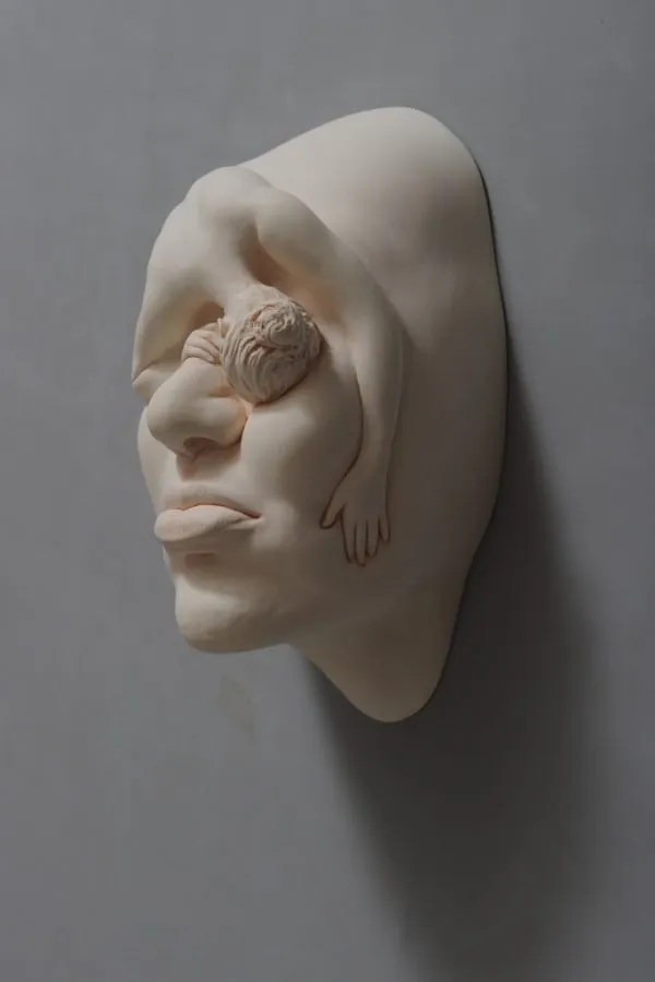 Rostro de la serie «Lucid Dream» de Johnson Tsang, con una mano y un mechón emergiendo del ojo
