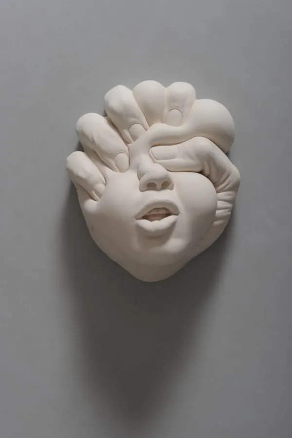 Rostro de la serie «Lucid Dream» de Johnson Tsang, con las manos moldeando una sonrisa forzada