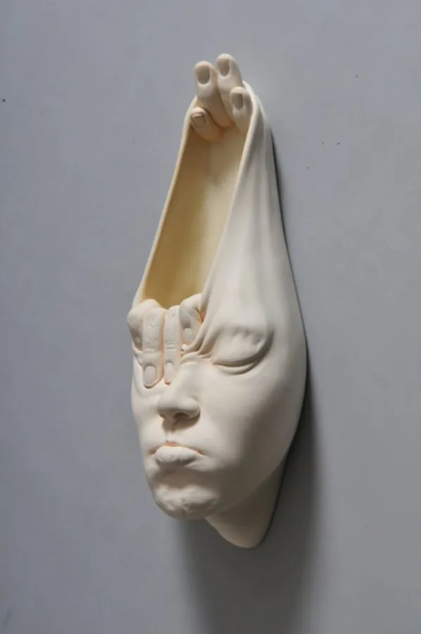 Rostro de la serie «Open Mind» de Johnson Tsang, con la cabeza abierta como una bolsa sostenida por una mano