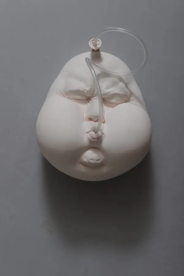 Escultura de la serie «Re-Mind» de Johnson Tsang, con un tubo que sale de la propia boca