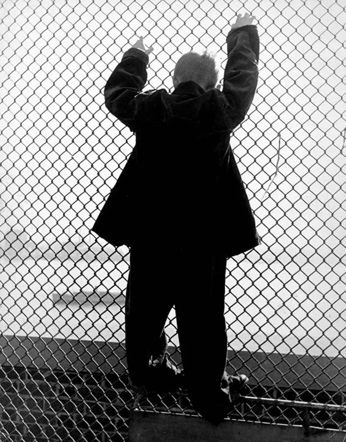 Paciente aferrado a la valla del recinto exterior del Hospital Pilgrim State (Alfred Eisenstaedt, 1938)