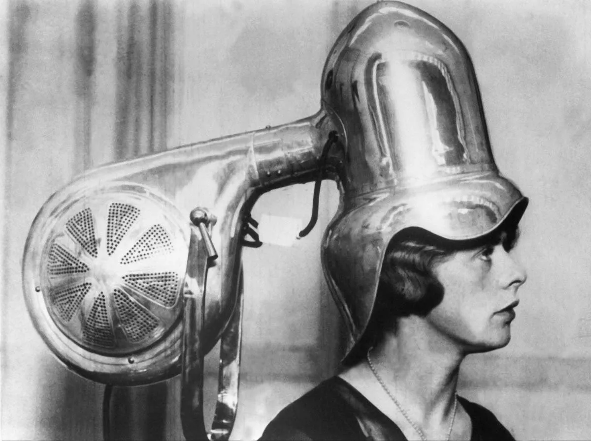 Secador de casco metálico de gran tamaño sobre la cabeza de una mujer