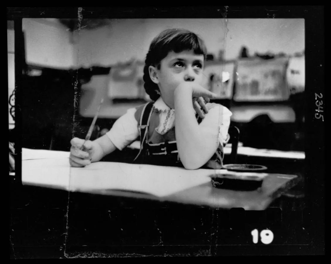 Niño girándose hacia la cámara en su pupitre escolar