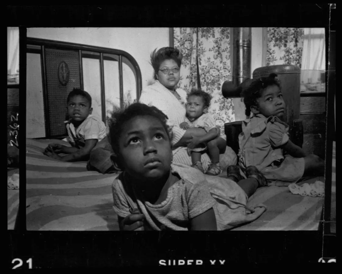 Madre e hijos sobre una cama en su vivienda humilde, Chicago 1949