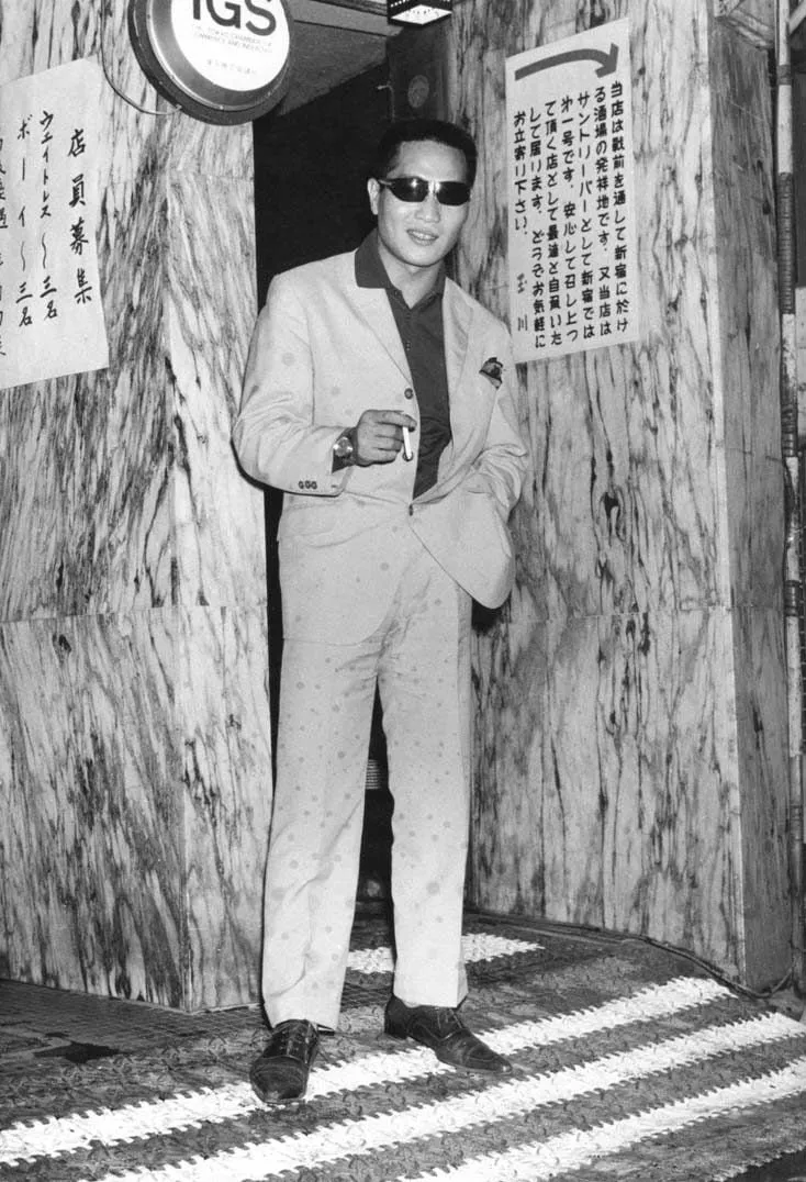 Watanabe Katsumi: hombre con gafas de sol en la entrada de un local en Kabukicho